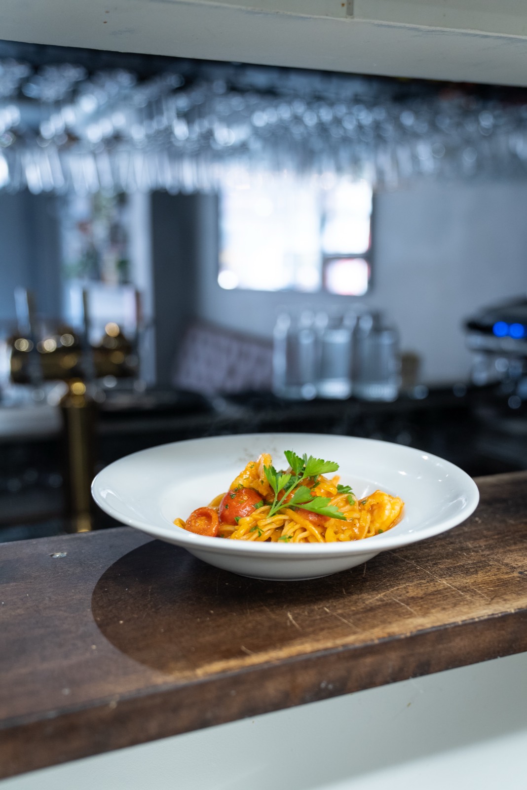 A single plate of pasta on the wooden counter.